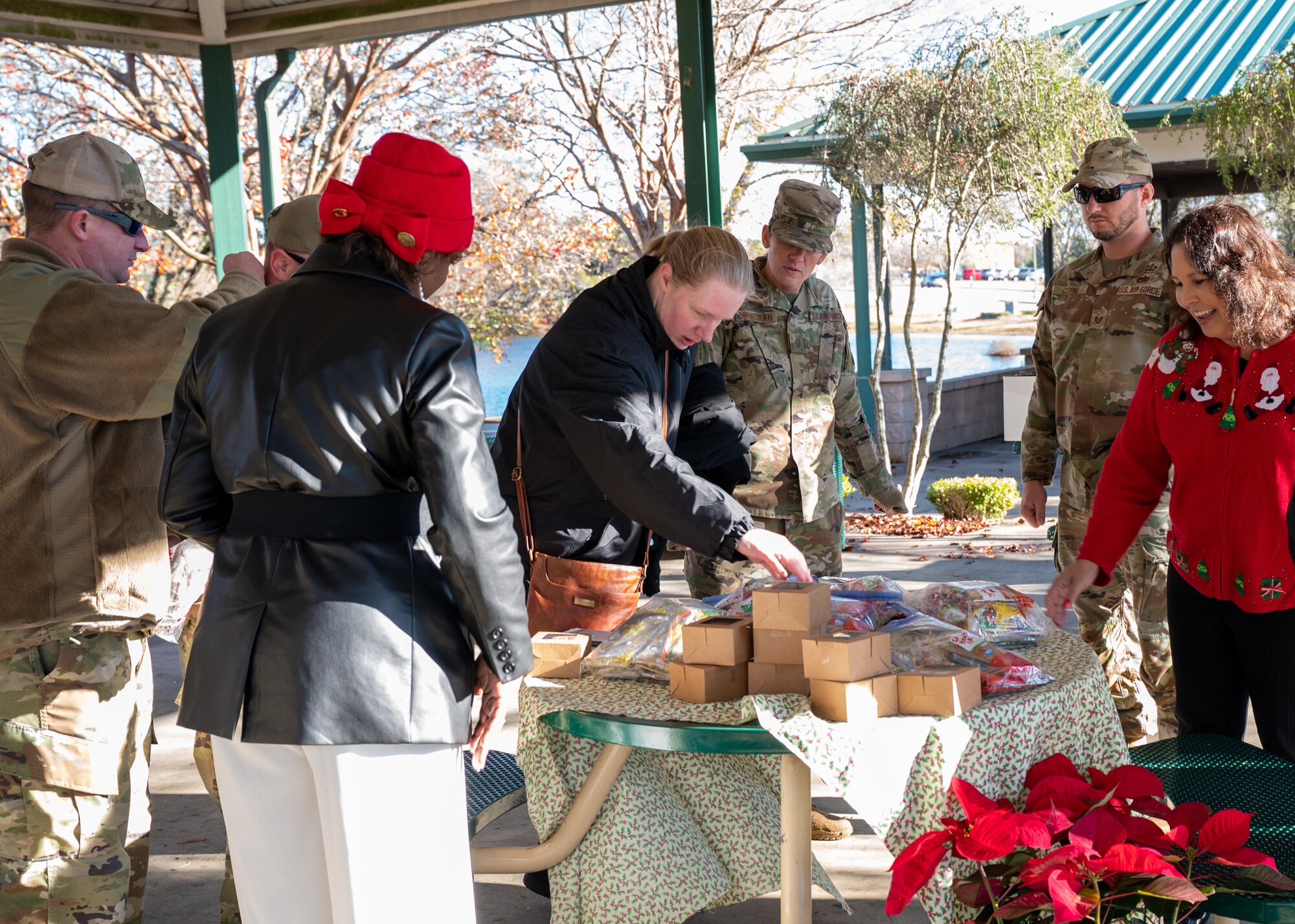 Men and women sort and arrange donated candy boxes and good bags on a table outside.