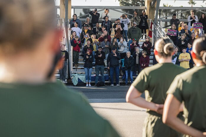 Families and guests of Fox Company, 2nd Recruit Training Battalion, cheer during a motivational run at Marine Corps Recruit Depot San Diego, Dec. 14, 2023. The motivational run is the final training event new Marines complete before graduating, which consists of a three-mile run throughout the Depot. (U.S. Marine Corps photo by Lance Cpl. Jacob B. Hutchinson)