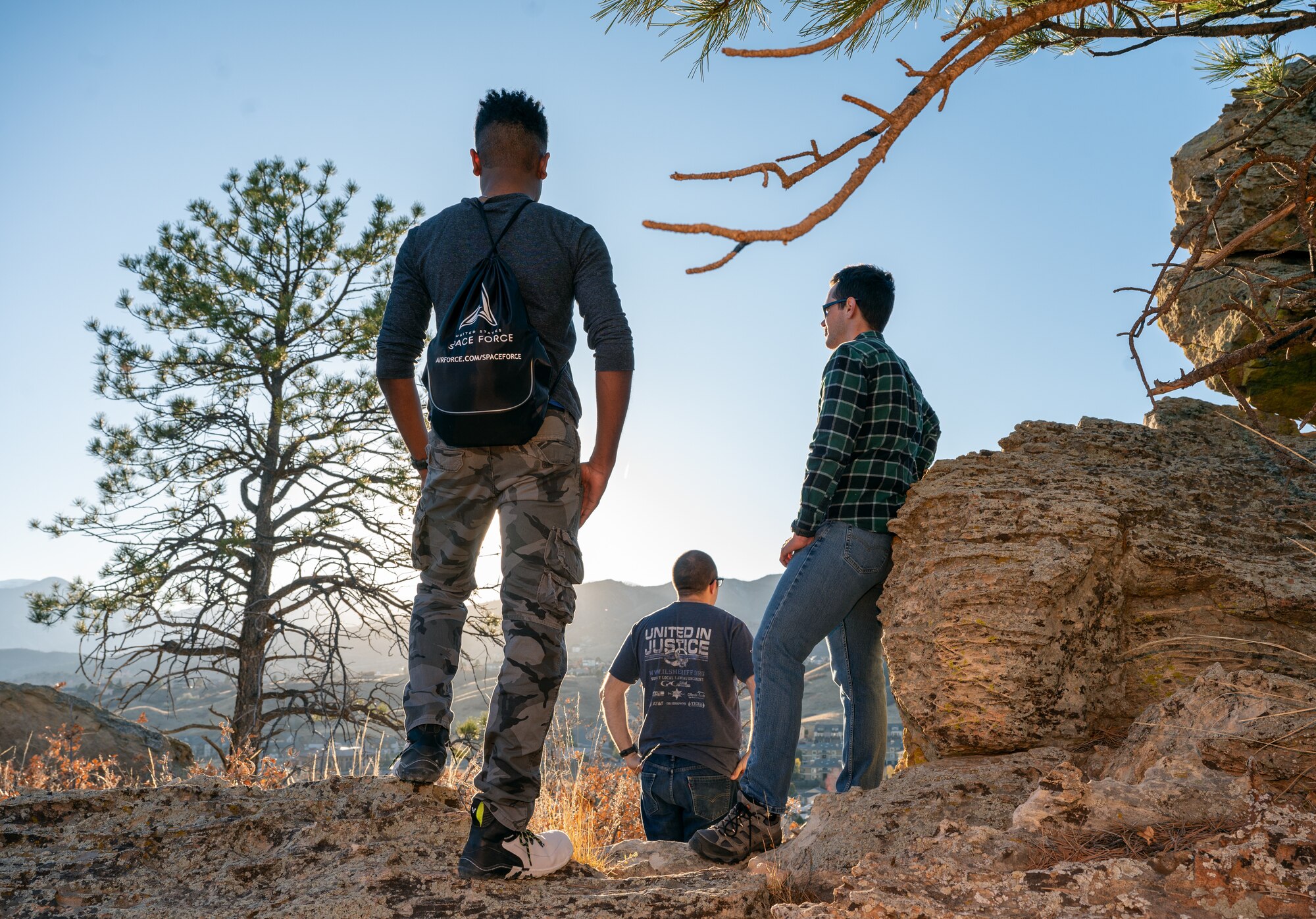 3 Guardians stand on a mountain looking out over the Colorado Springs area.