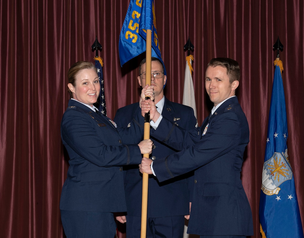 A woman in air force uniform passes a flag to a man in an air force uniform