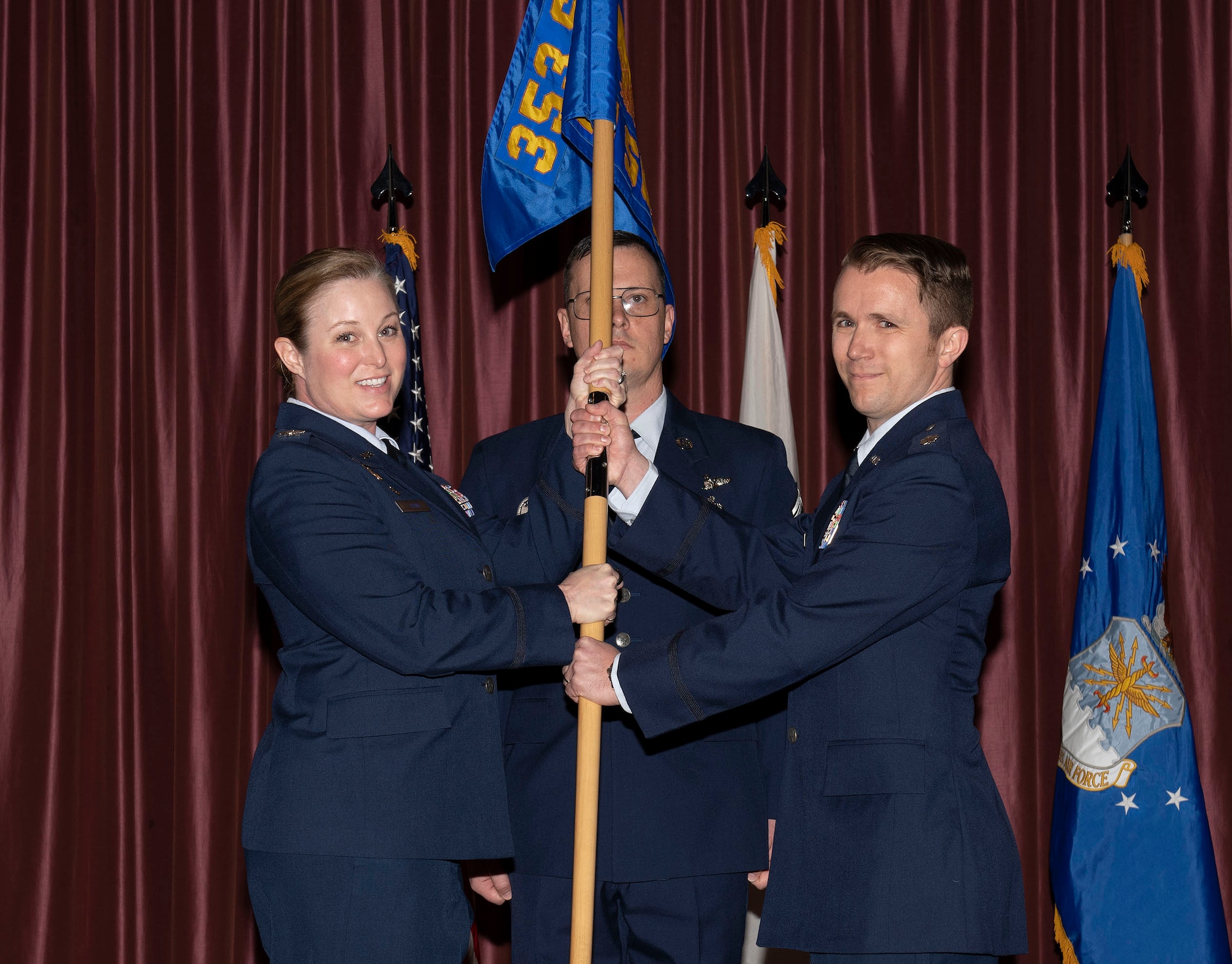 A woman in air force uniform passes a flag to a man in an air force uniform
