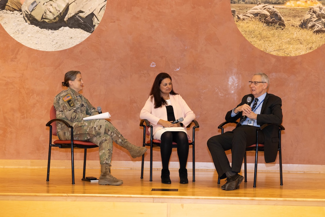 Three people on the stage have a discussion.