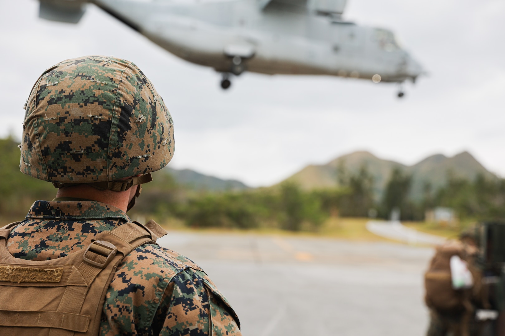 A U.S. Marine with Marine Aviation Logistics Squadron 36 observes the takeoff of an MV-22B Osprey assigned to Marine Medium Tiltrotor Squadron 262 during Stand-in Force Exercise 24 at Camp Hansen, Okinawa, Japan, Dec. 1, 2023. SIFEX 24 is a division-level exercise involving all elements of the Marine Air-Ground Task Force focused on strengthening multi-domain awareness, maneuver, and fires across a distributed airtime environment.