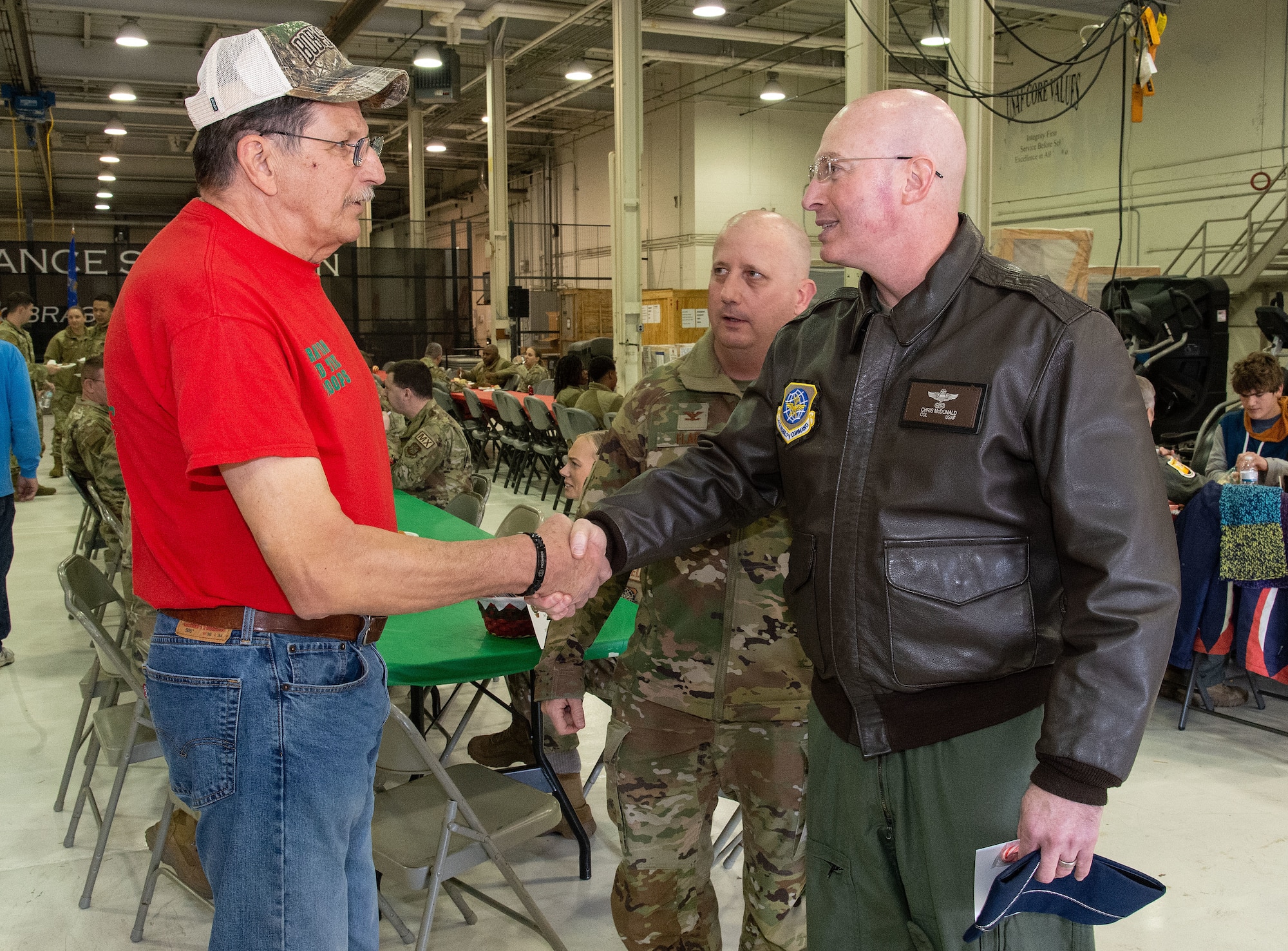 U.S. Air Force Col. Chris McDonald, right, 436th Airlift Wing commander, shakes hands with retired U.S. Air Force Reserve Master Sgt. Robert ‘Bob’ Reese, founder and organizer of Operation Feed the Troops at Dover Air Force Base, Delaware, Dec. 13, 2023. This year, more than 800 meals were served to active duty, Reserve and civilians, as well as their family members during two different meals for day and night shift workers (U.S. Air Force photo by Roland Balik)