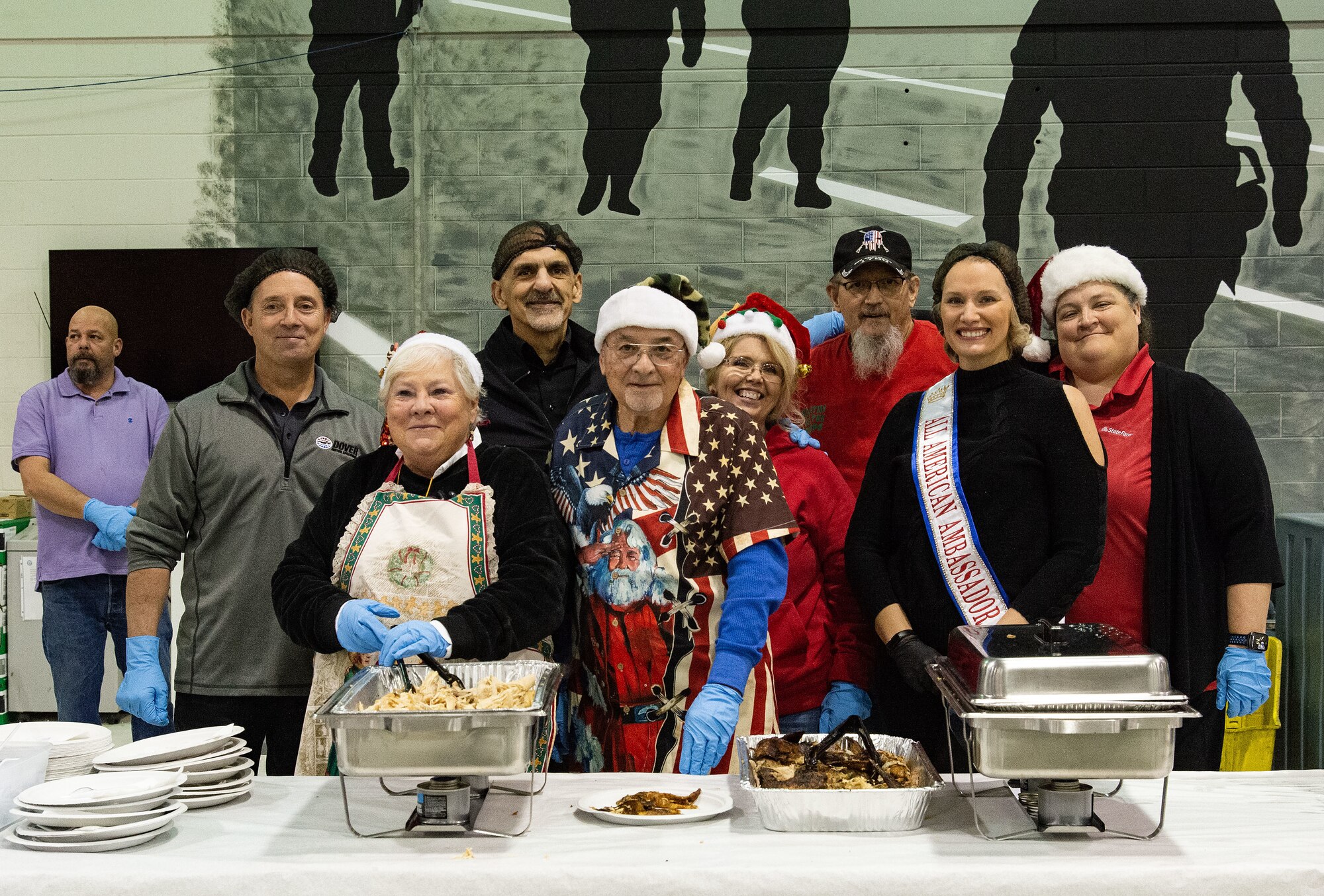 A group of Operation Feed the Troops food line night meal servers gather for a photo at Dover Air Force Base, Delaware, Dec. 13, 2023. OFTT volunteers served the annual traditional dinner consisting of turkey, stuffing, green beans, corn, gravy, sweet potatoes, cranberry sauce and a variety of desserts and assorted beverages. (U.S. Air Force photo by Roland Balik)
