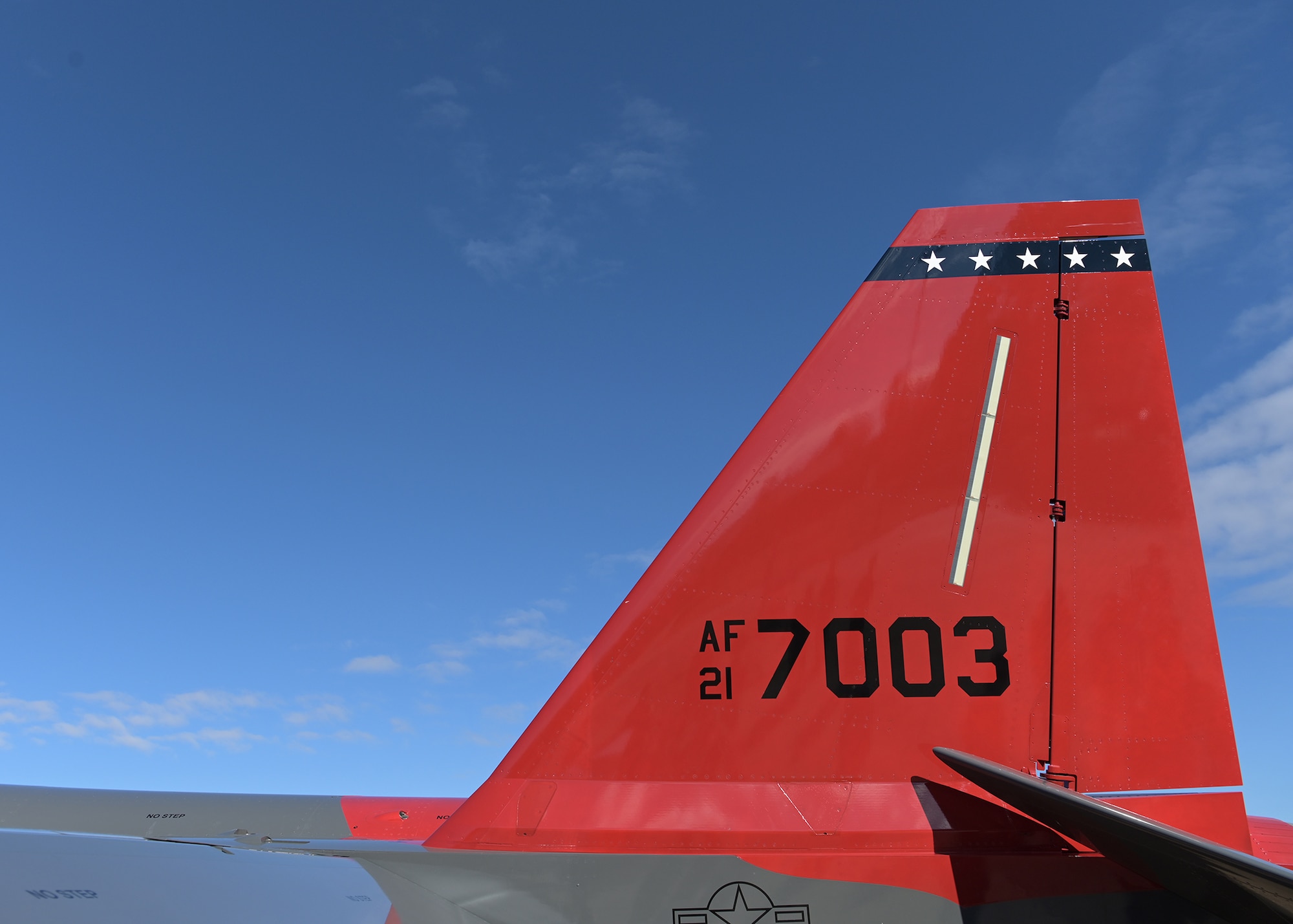 The twin red tails of the T-7A Red Hawk are seen against a blue skyline.