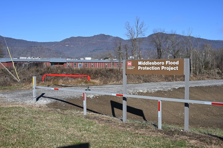 Sign saying Middlesboro Flood Project by freshly plowed earth by creek.