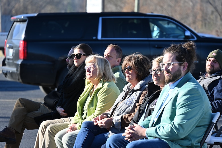 Audience sits in cold chairs watching ceremony.