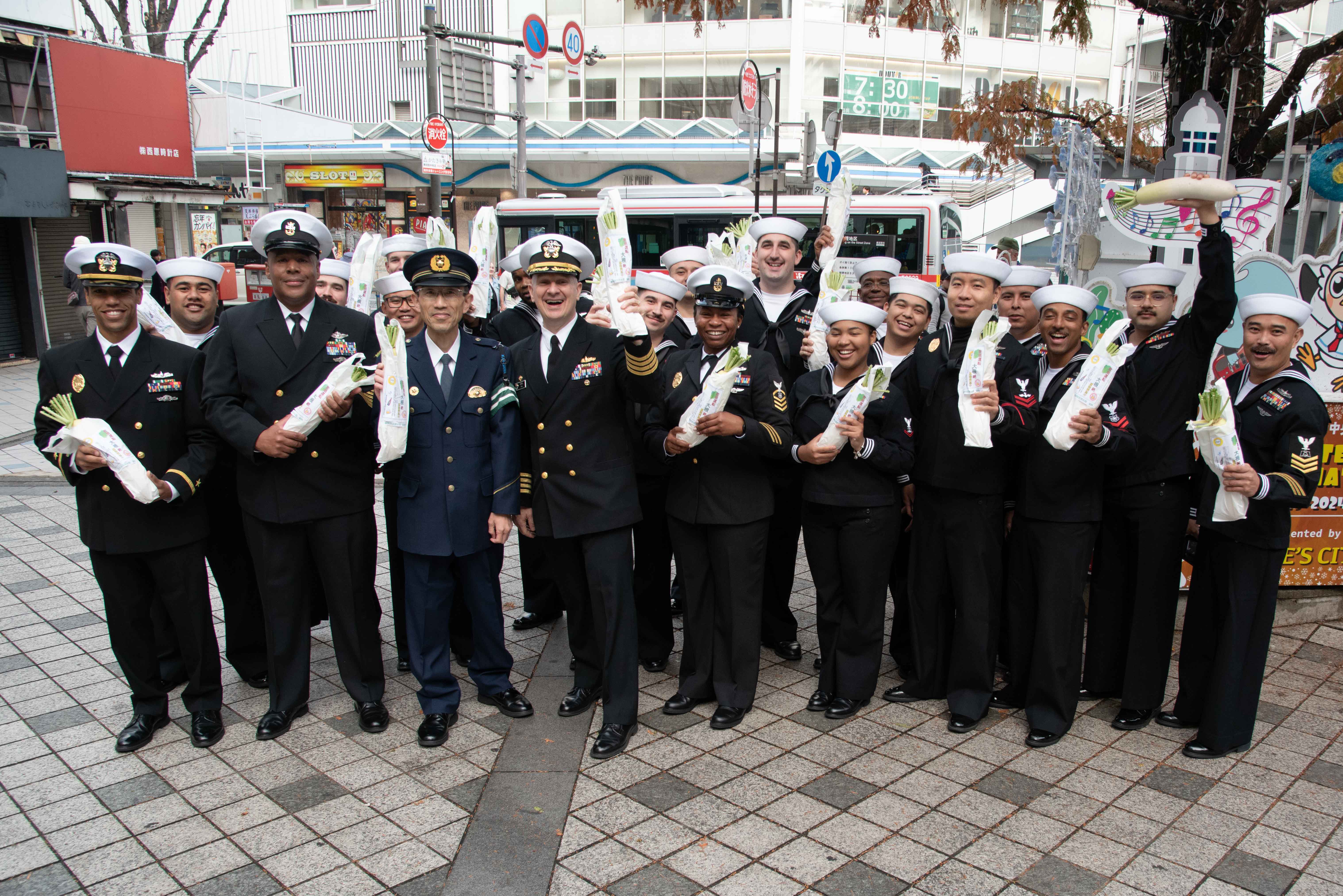 Navy sailors and Japanese police station members gather together in celebration to take a photo.