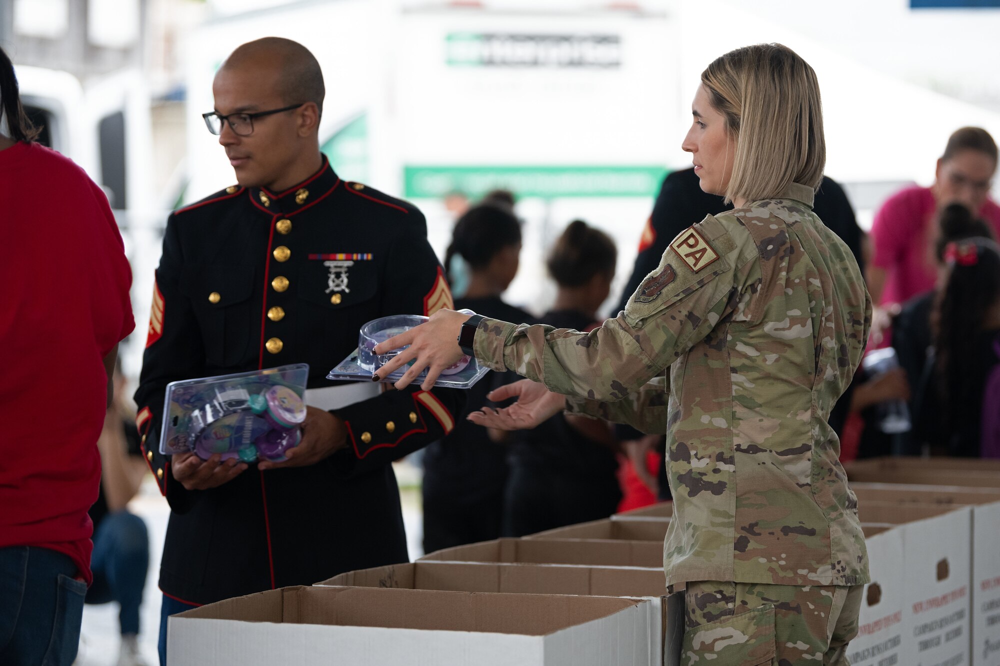 U.S Marine Corps Sgt. Yadiel Burgos Benitez, a Toys for Tots coordinator, assigned to Det. 1 Landing Support Company, Combat Logistics Regiment 45, 4th Marine Logistics Group, and  U.S. Air Force Airman 1st Class Victoria Jewett, a public affairs specialist with the 156th Wing, delivers toys to children at during a toy distribution at Dr. Julio Henna Elementary School, San Juan, Puerto Rico, Dec. 14, 2023. The event was part of the campaign with Toys for Tots, where PRANG members partnered with Marines to distribute more than 200 toys to children at a local school. (U.S. Air National Guard photo by Airman 1st Class Gisselle Toro-Caraballo)