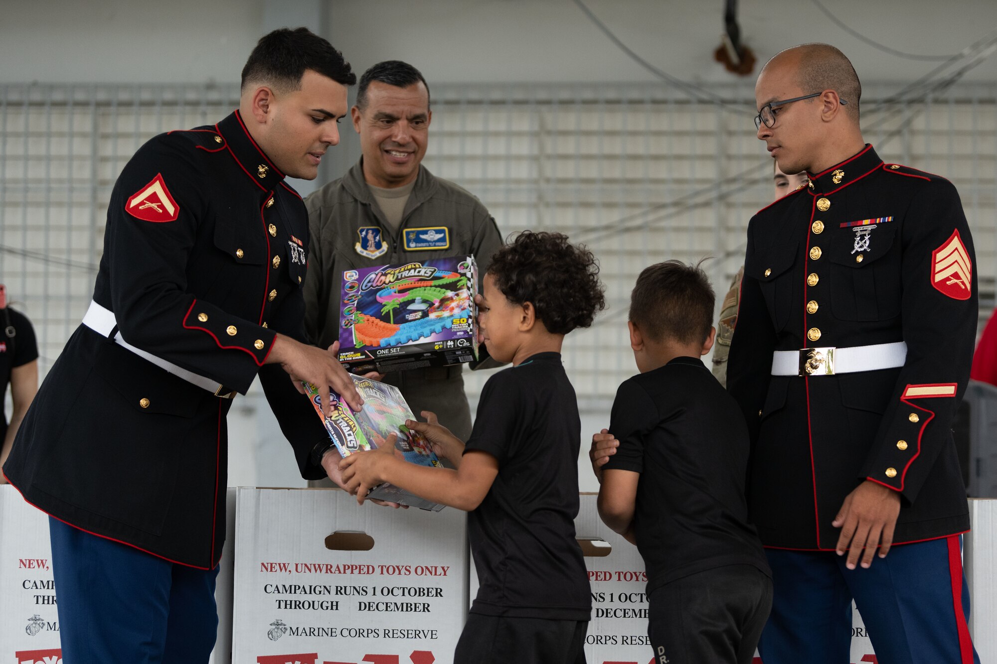 U.S. Air Force Col. Evaristo Orengo III., the 156th Wing commander, Puerto Rico Air National Guard, U.S. Marine Lance Cpl. Jose Gonzalez Gomez, a Toys for Tots assistant coordinator, and Sgt. Yadiel Burgos Benitez, a Toys for Tots coordinator, both assigned to Det. 1 Landing Support Company, Combat Logistics Regiment 45, 4th Marine Logistics Group, distribute toys at Dr. Julio Henna Elementary School, San Juan, Puerto Rico, Dec. 14, 2023. The event was part of the campaign with Toys for Tots, where PRANG members partnered with Marines to distribute more than 200 toys to children at a local school. (U.S. Air National Guard photo by Airman 1st Gisselle Toro-Caraballo)