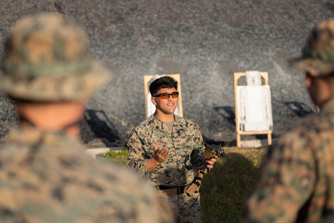 U.S. Marine Corps Staff Sgt. Payton Garcia, a member of the Marine Corps Shooting Team, teaches the fundamentals of holding an M18 pistol during the Marine Corps Marksmanship Competition Far East on Camp Hansen, Okinawa, Japan, Dec. 11, 2023. MCMC-Far East is an annual two week event held to improve Marines’ marksmanship, combat readiness and weapon proficiency. Marines utilize the first week to learn various techniques and fundamentals from members of the Marine Corps Shooting Team, and compete the following week as individuals and teams. (U.S. Marine Corps photo by Cpl. Vincent Pham)
