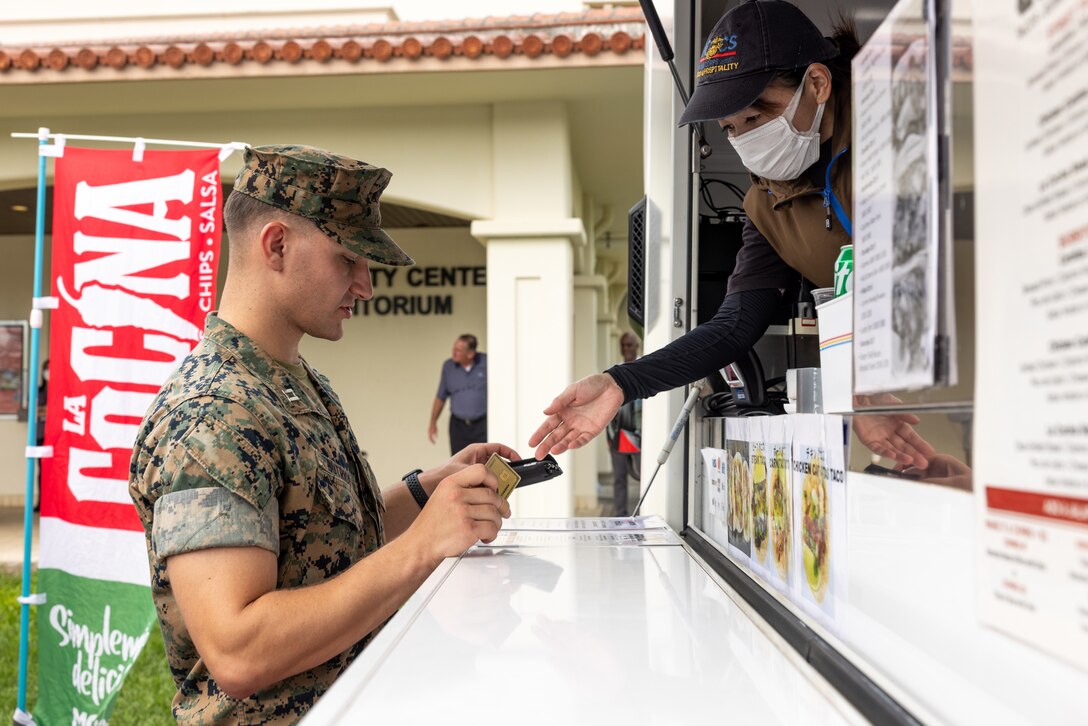 U.S. Marine Corps Capt. Charles Butrico, defense council with Legal Services Support Section, Marine Corps Installations Pacific, orders a meal from a food truck during the opening day of the Mobile Feeding Pilot Program at the Foster Community Center, Camp Foster, Okinawa, Japan, Oct. 4, 2023. To boost the quality of life for service members in the pacific region, Marines and Navy Sailors may now use their meal entitlements on the Chef Shack and La Cocina Marine Corps Community Services food trucks instead of mess halls by showing their military ID cards. The program is currently only available on Camp Foster, however Food Service Operations plans to expand their outreach to every Marine Corps installation in the Pacific. (U.S. Marine Corps photo by Cpl. Thomas Sheng)