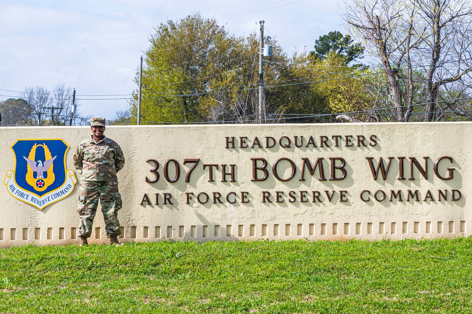 An Airman stands in front of a sign that reads "Headquarters: 307th Bomb Wing Air Reserve Command".