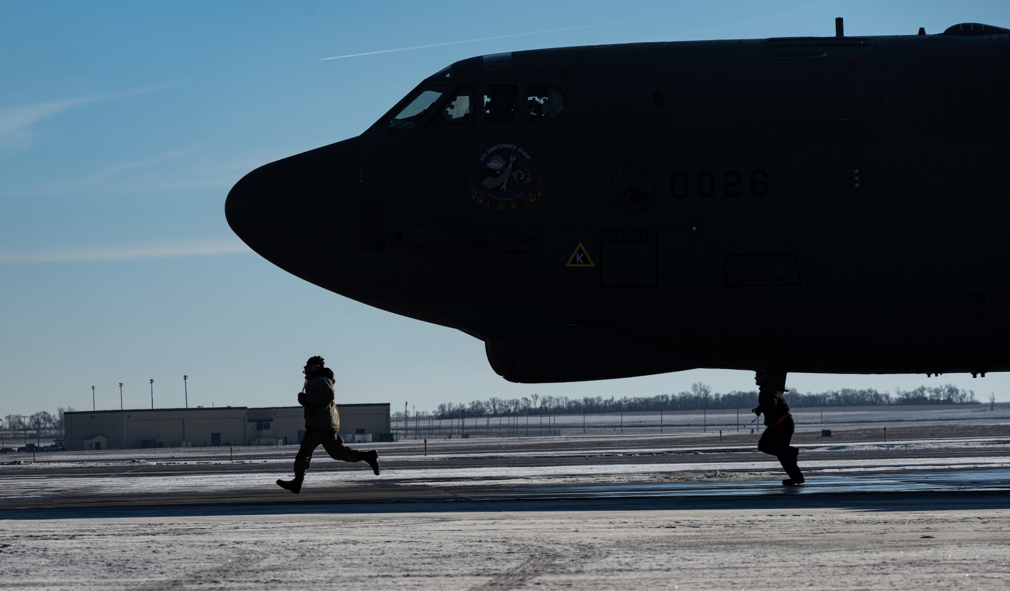 Airmen assigned to the 5th Aircraft Maintenance Squadron run to their position on the flight line during SURGE Week at Minot Air Force Base, North Dakota, Dec. 13, 2023. SURGE Week allows the 5th Bomb Wing to showcase its airpower. (U.S. Air Force photo by Airman 1st Class Alyssa Bankston)