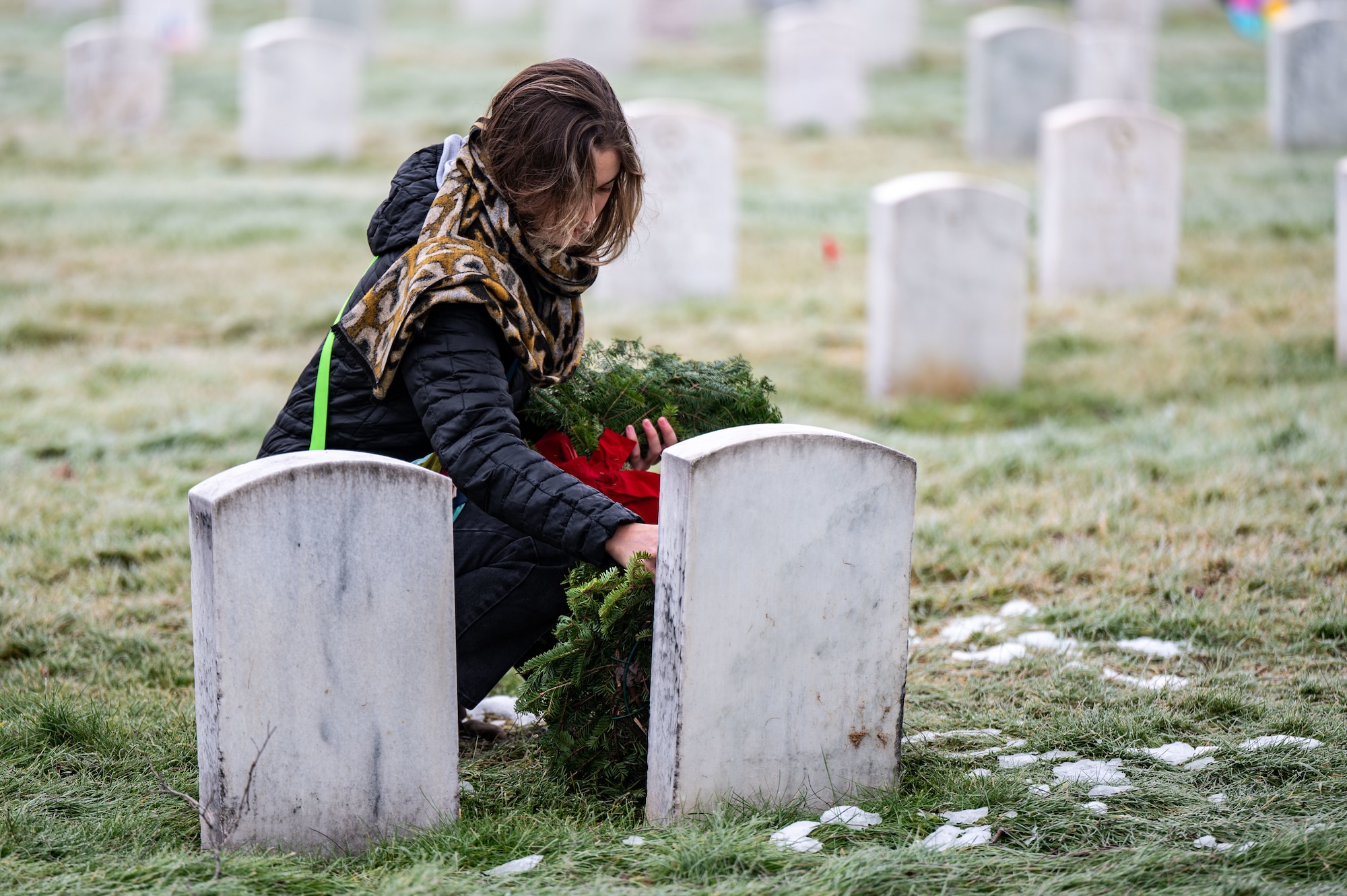 A woman laying a wreath on a gravestone
