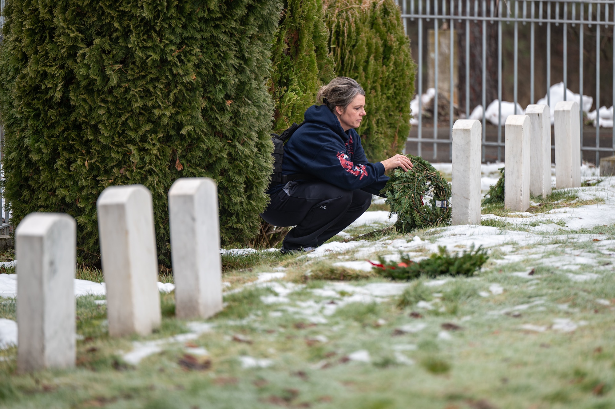 A woman laying a wreath on a gravestone