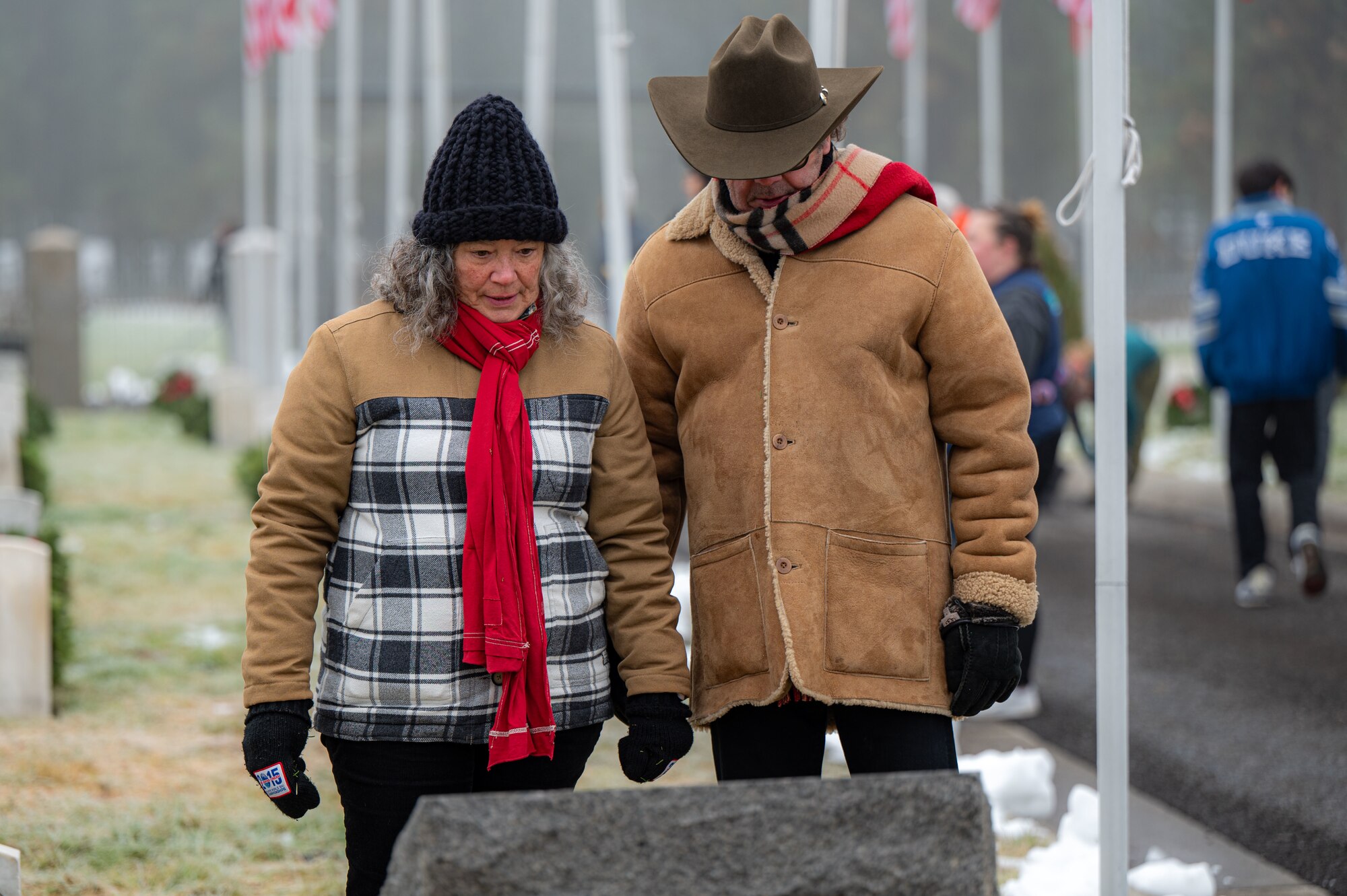 A couple stands in front of a gravestone