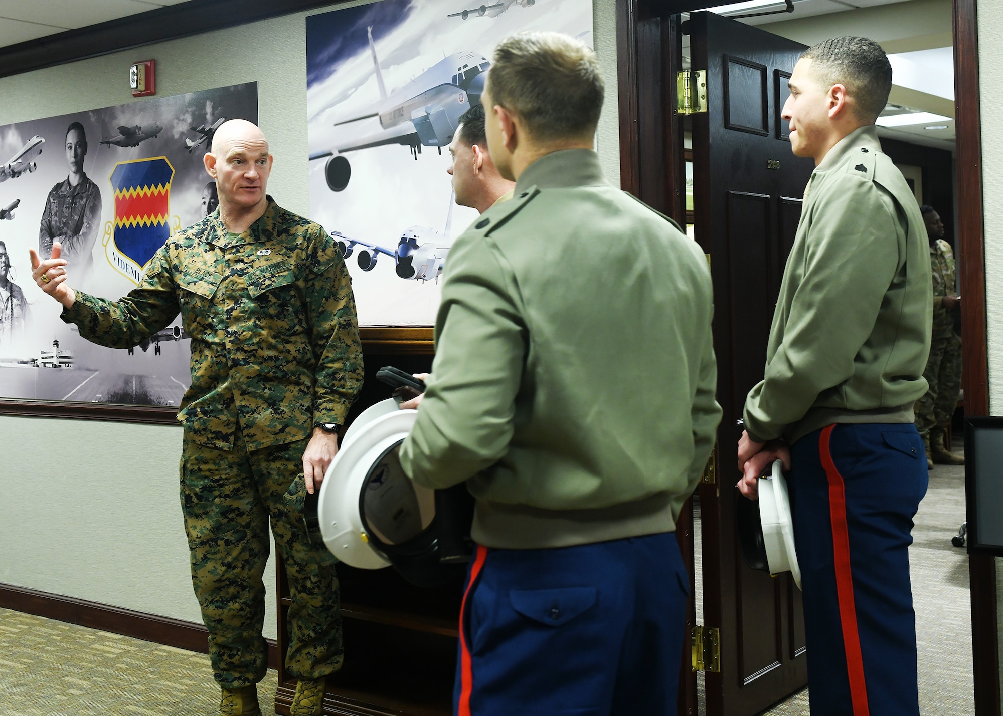 Senior leader in fatigues speaks in hallway to Marine recruiters.