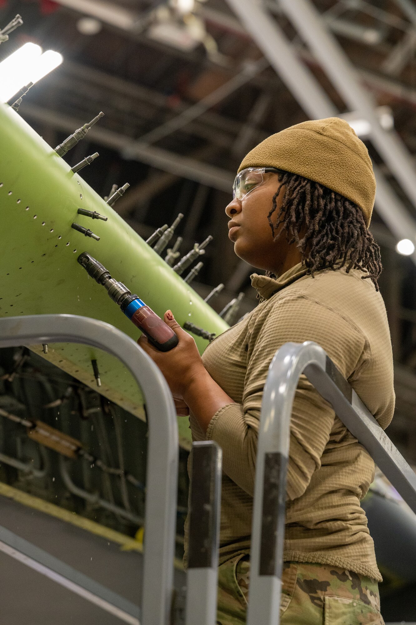 Senior Airman Tori Harkness, 434th Maintenance Squadron aircraft structural maintenance journeyman, replaces one of over 12,000 rivets on a KC-135R Stratotanker. She is standing on a metal stand while conducting the repair with a tool in-hand.