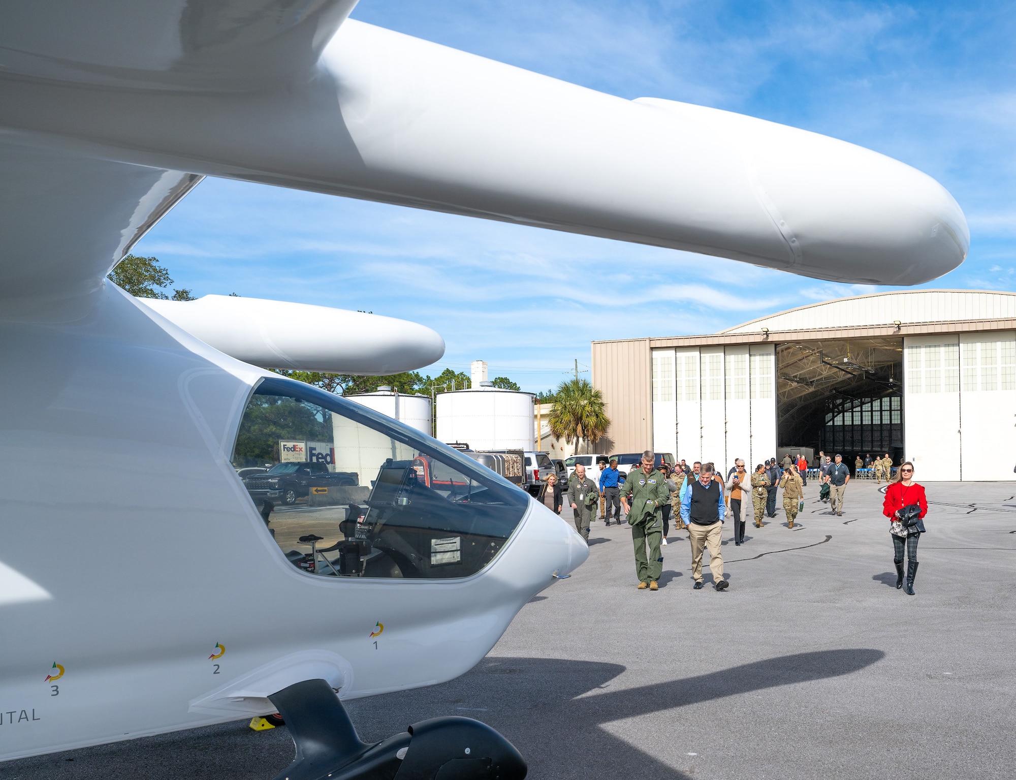A group of people walk towards an electric aircraft on the flight line.
