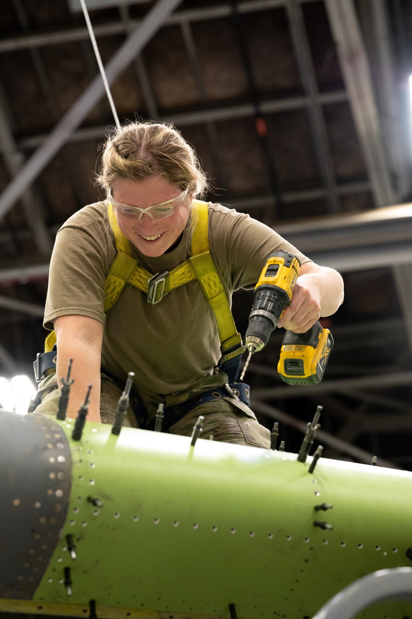 Master Sgt. Kelsey St. Clair, 434th Maintenance Squadron aircraft structural maintenance craftsman, works on the wing of a KC-135R Stratotanker. She is kneeling on top of the wing with an electric-powered screw driver in her hand and rivets in the foreground.