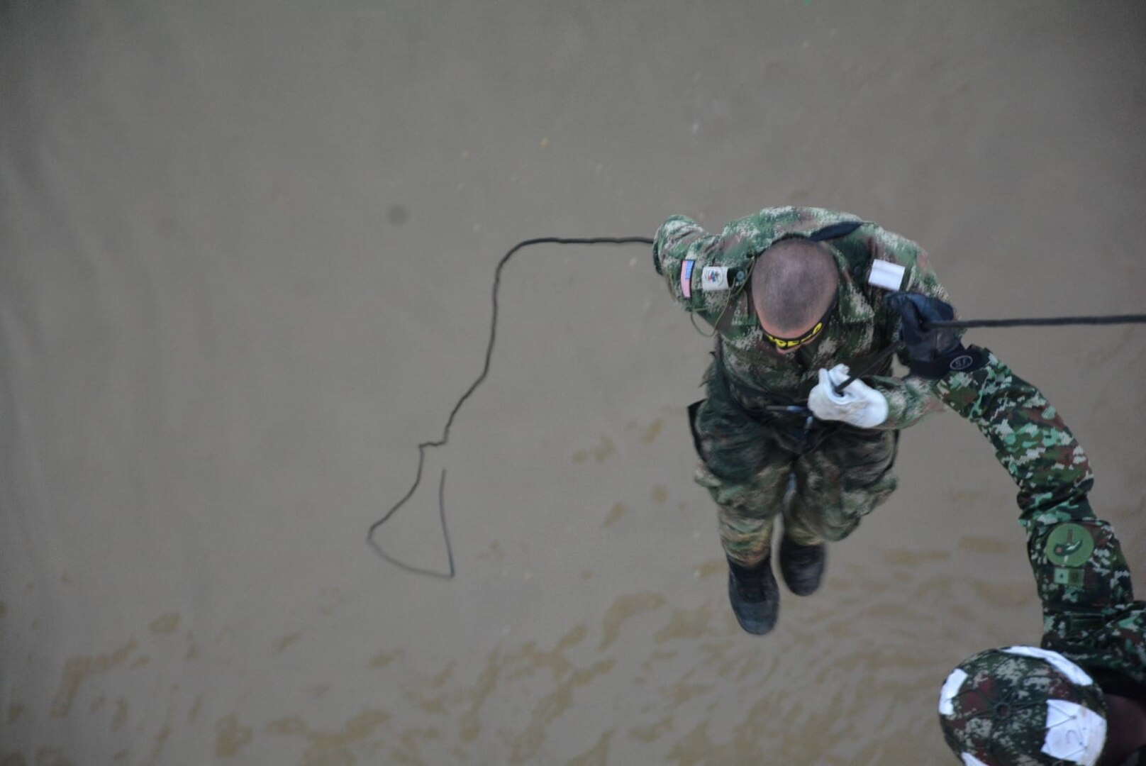 A soldier rappels down a rope.