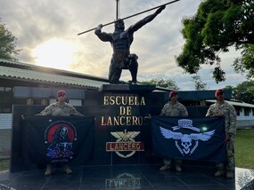 Soldiers pose for a photo in front of a statue.