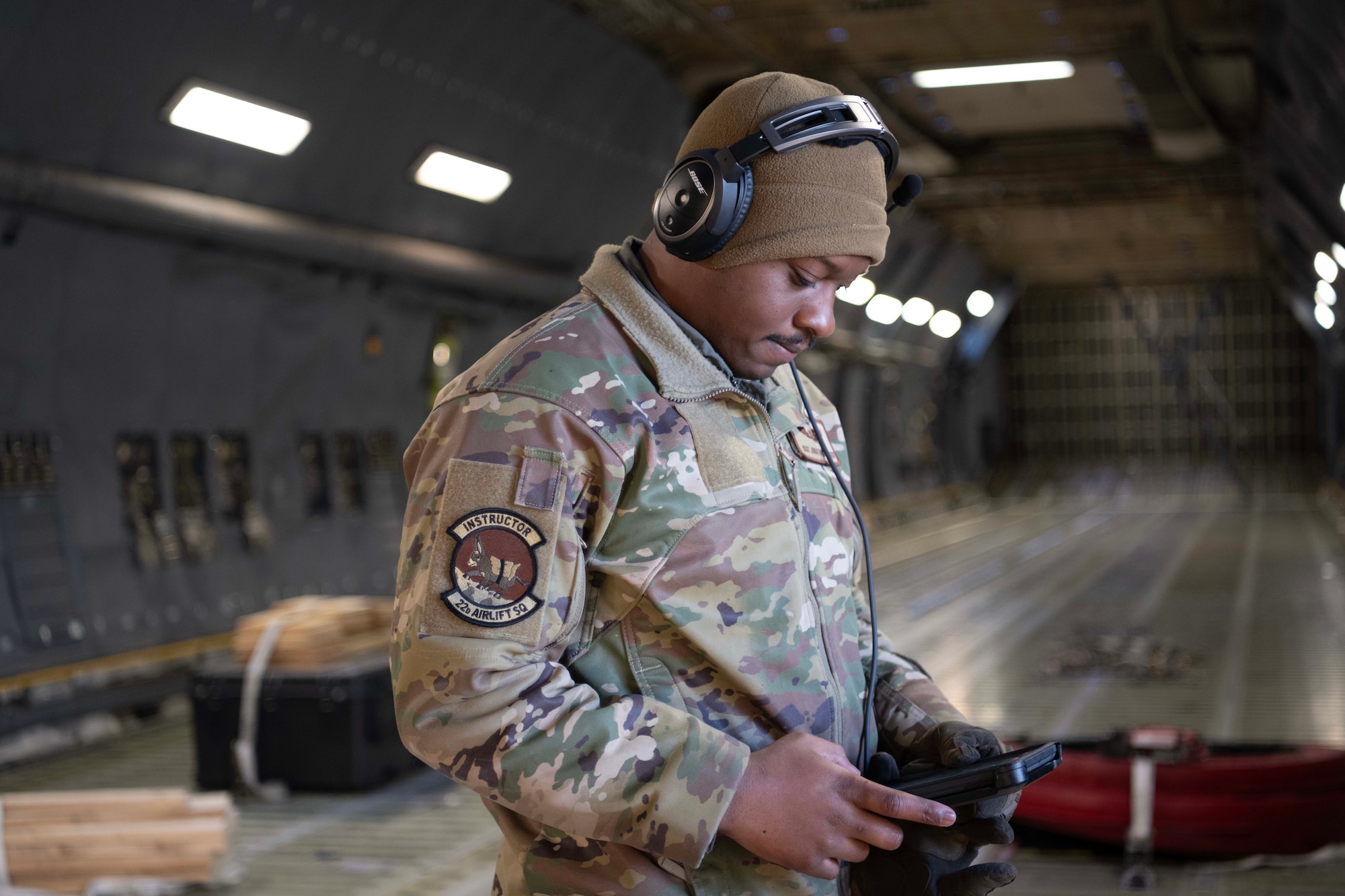 An Airman looks at an electronic device inside the cargo bay of a military aircraft