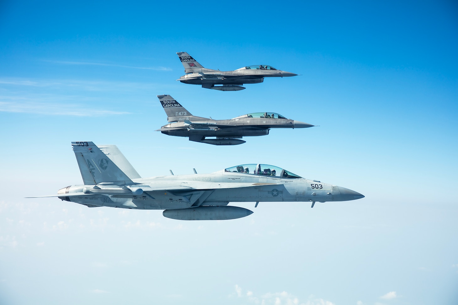 A Navy Reserve E/A-18G Growler flies alongside two Air National Guard F-18 Super Hornets