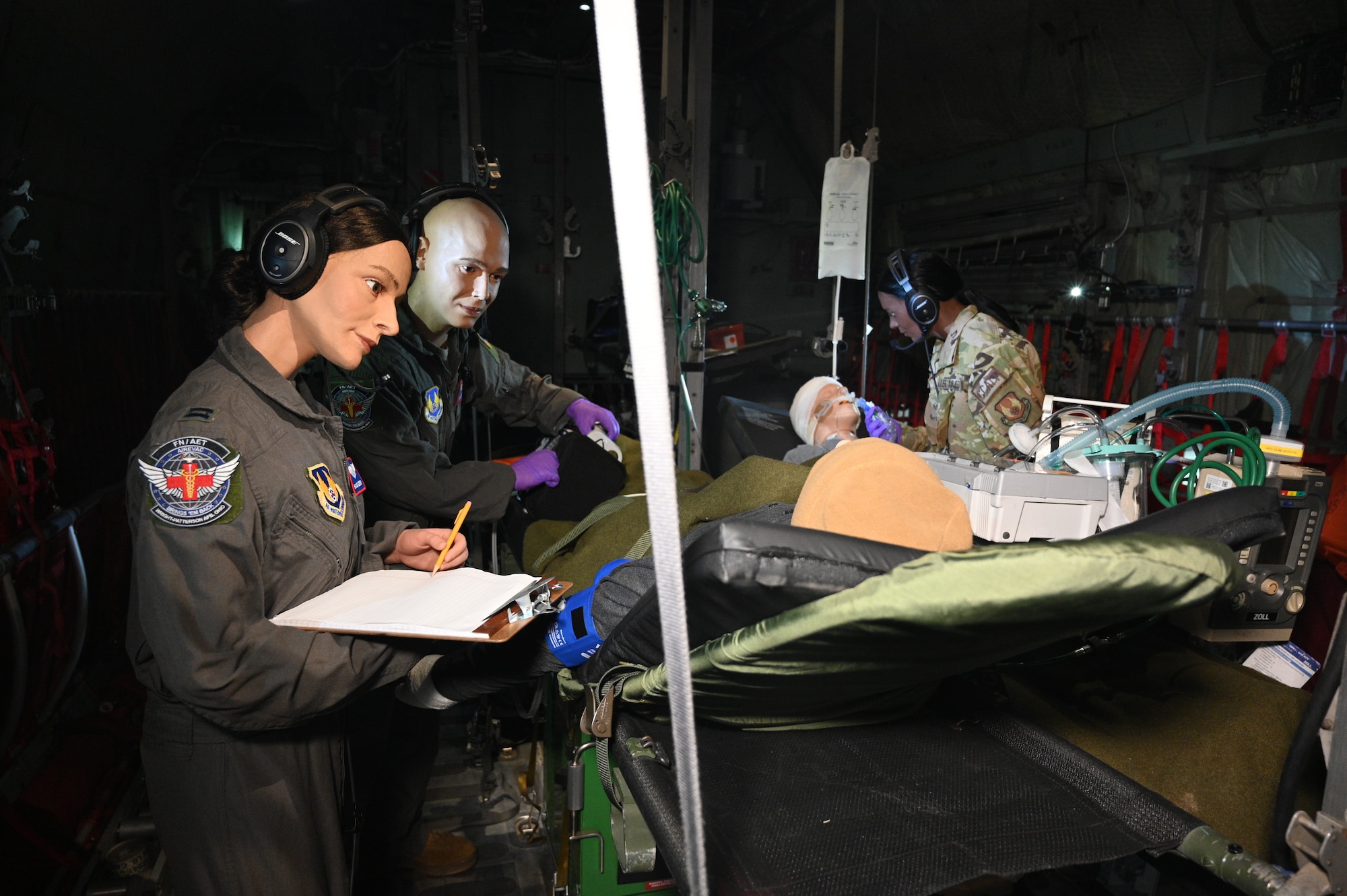 Interior image of the C-130 medical transport plane with mannequins dressed in service uniforms, treating patients.