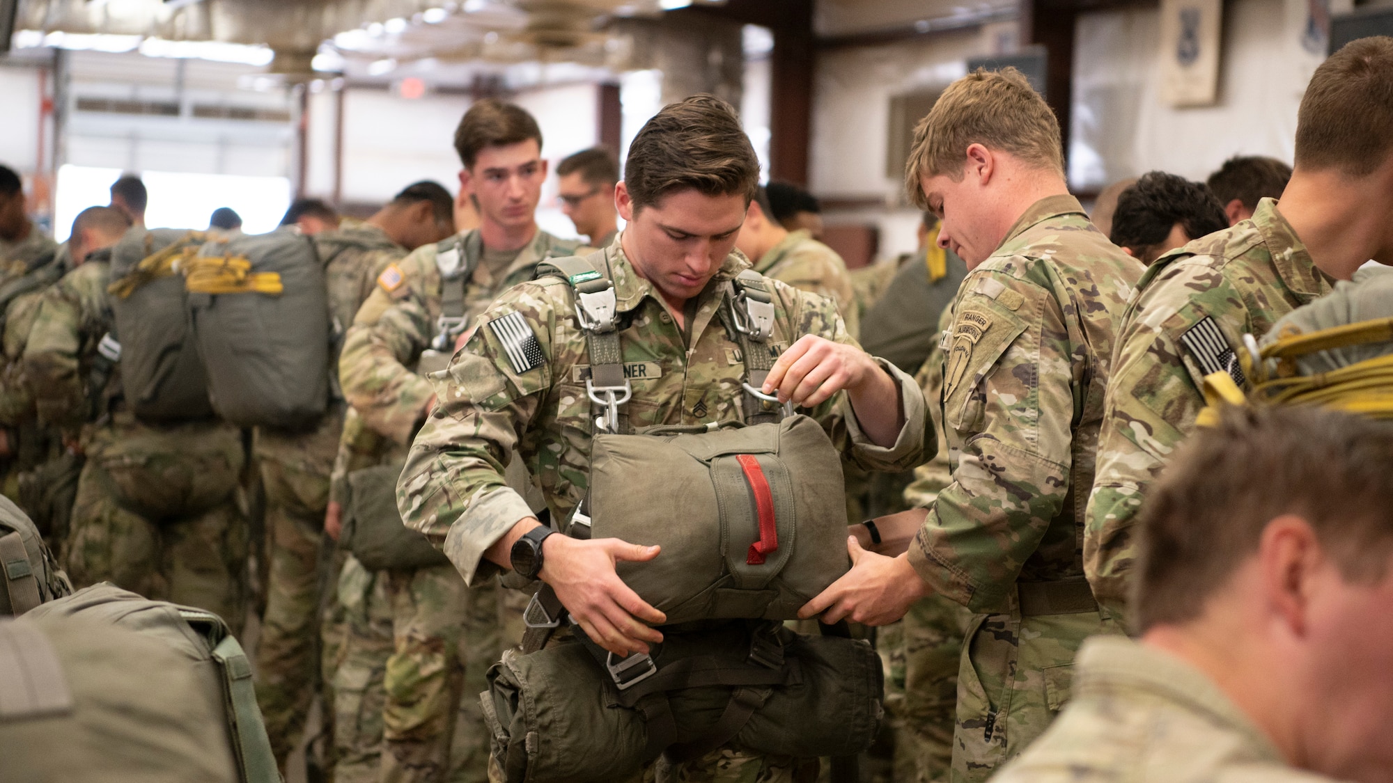 people in military uniforms stand in lines and check each others equipment before parachuting out of an airplane