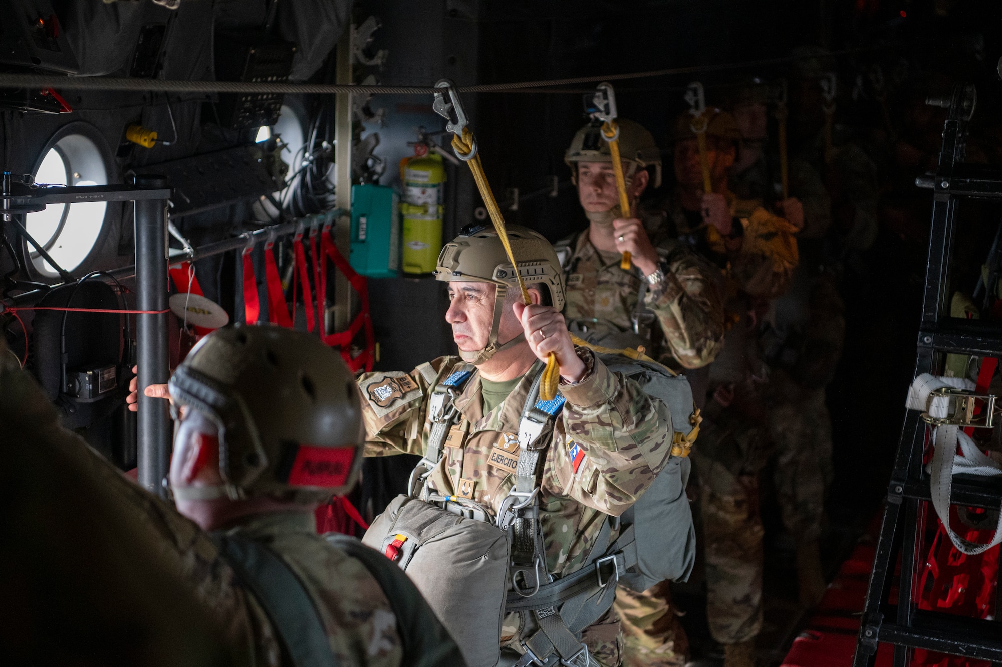 people in military uniforms stand inside an aircraft preparing to parachute out of it
