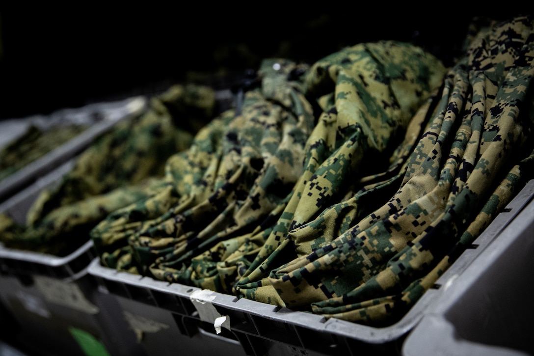 Combat Woodland Jackets sit in a plastic container at the Individual Issue Facility (IIF), located in Building 1211 on Birch Street, on Marine Corps Base Camp Lejeune, North Carolina, Dec. 7, 2023. The IIF provides Marines items such as Kevlar helmets, flak vests and cold-weather gear, to ensure they are ready for training and deployments. (U.S. Marine Corps photo by Cpl. Jorge Borjas)