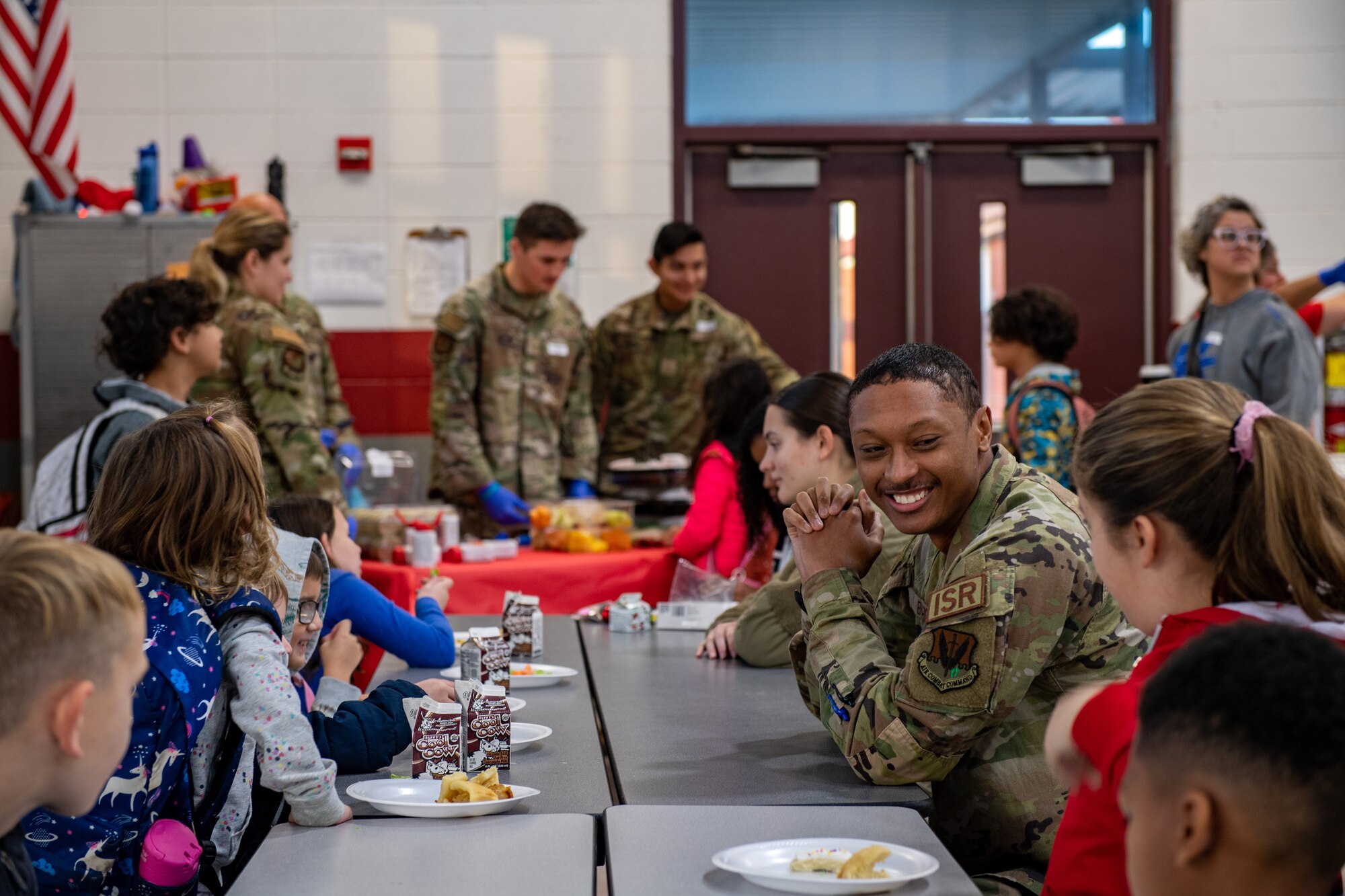 U.S. Air Force Airman 1st Class Jarren Byrd, 347th Operations Support Squadron intel analyst, listens to students during breakfast at James L. Dewar Elementary School in Valdosta, Georgia, Dec. 15, 2023. Byrd volunteered his time to the Dewar Deployment Breakfast Club in an effort to support students who have a parent deployed. (U.S. Air Force photo by Courtney Sebastianelli)