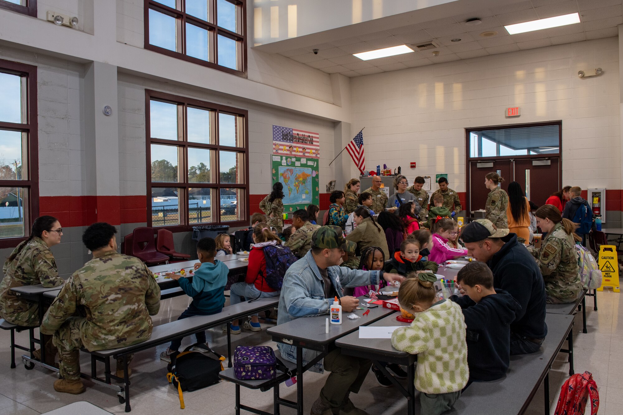 U.S. Air Force Airmen from Moody Air Force Base, serve breakfast to students at James L. Dewar Elementary School in Valdosta, Georgia, Dec. 15, 2023. Once a month, Dewar hosts the Deployment Breakfast Club for students who have a parent deployed. (U.S. Air Force photo by Courtney Sebastianelli)