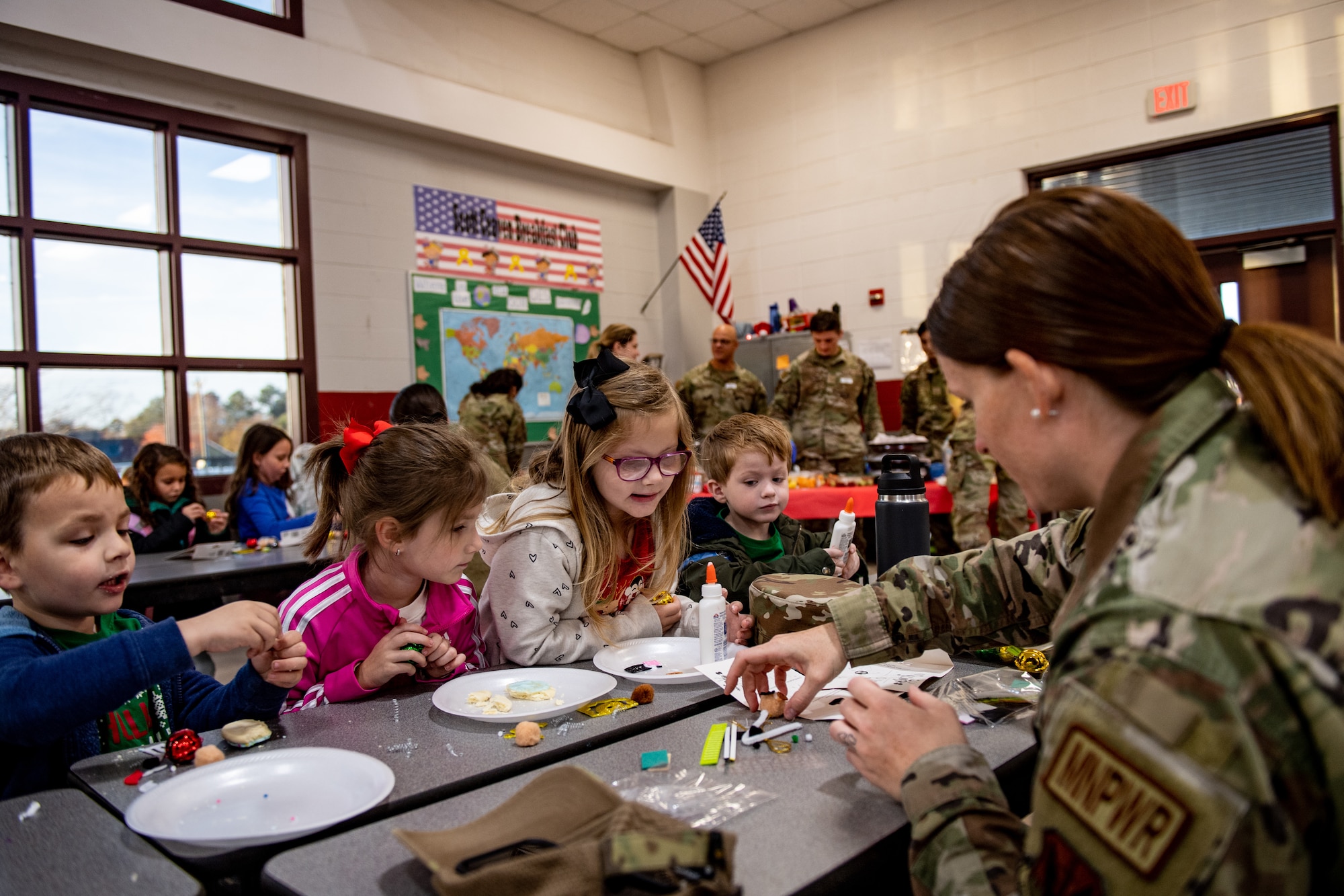 A U.S. Air Force Airman assigned to the 23rd Wing at Moody Air Force Base, Georgia, shows students how to put together a holiday ornament at James L. Dewar Elementary School in Valdosta, Georgia, Dec. 15, 2023. Once a month, Dewar Elementary hosts the Deployment Breakfast Club for students with a deployed parent. (U.S. Air Force photo by Senior Airman Courtney Sebastianelli)