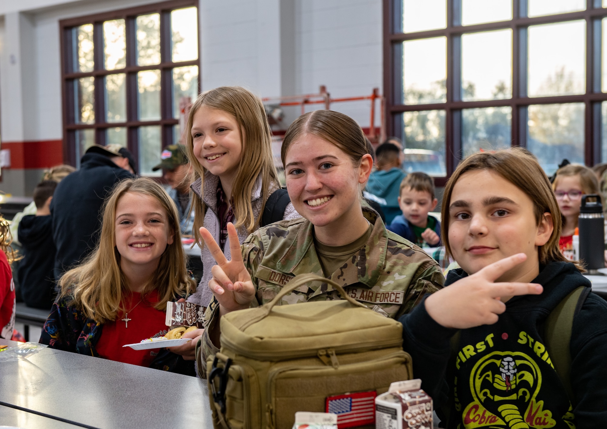 U.S. Air Force Airman 1st Class Olivia Dorsch, 347th Operations Support Squadron intel analyst, smiles with students at James L. Dewar Elementary School in Valdosta, Georgia, Dec. 15, 2023. Dorsch volunteered her time to talk with students who have parents deployed. (U.S. Air Force photo by Courtney Sebastianelli)