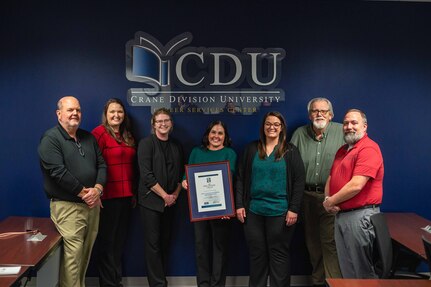 A group of people stand with a certificate for an award they won.