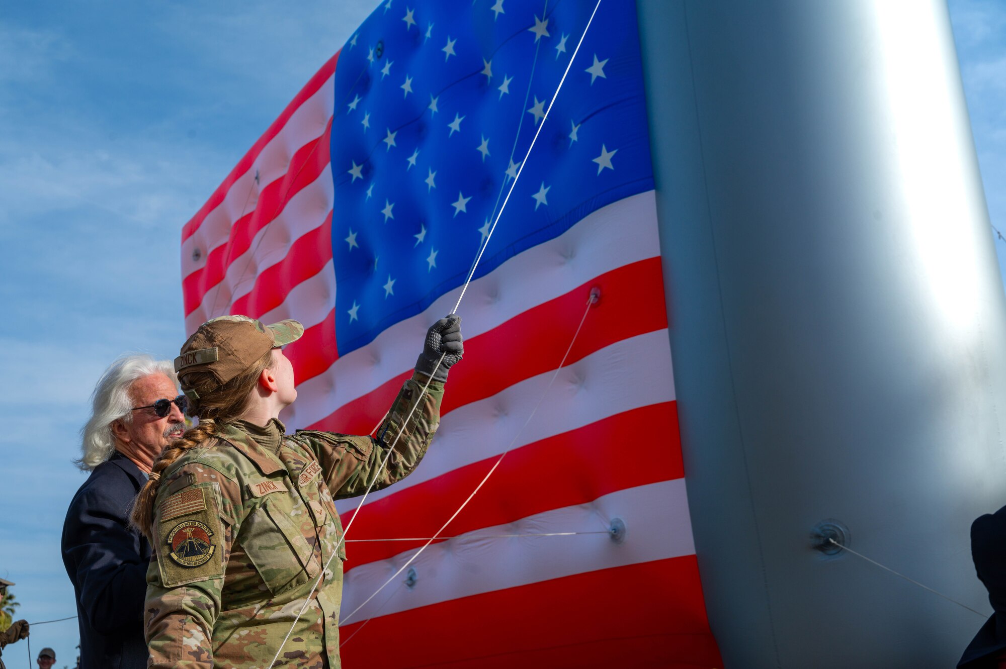 U.S. Air Force Airman First Class Hailey Zink, 56th Operational Medical Readiness Squadron aerospace medical assistant, guides an American flag balloon during the Fiesta Bowl Parade, Dec. 16, 2023, in Phoenix, Arizona.