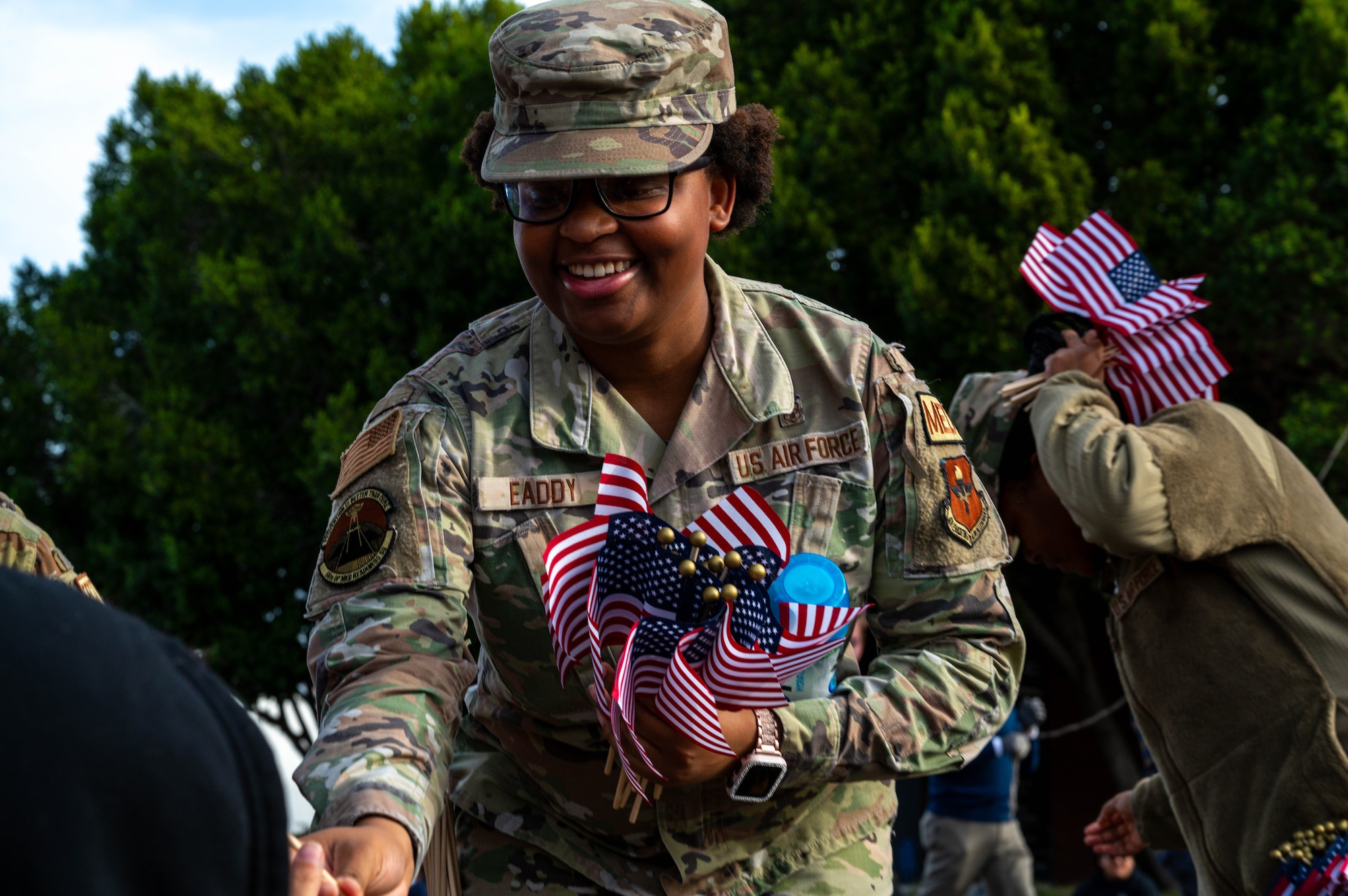 U.S. Air Force Senior Airman Ayauna Eaddy-Riccardi, 56th Operational Medical Readiness Squadron mental health technician, hands out flags to spectators during the Fiesta Bowl Parade, Dec. 16, 2023, in Phoenix, Arizona.