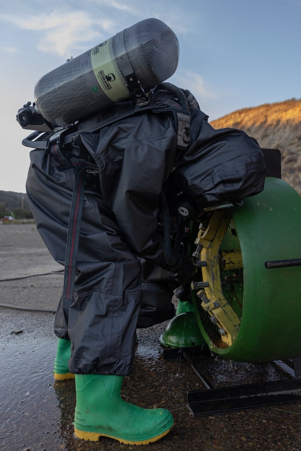 U.S. Marine Corps Lance Cpl. Michael Dreckman, a chemical, biological, radiological, and nuclear specialist with Marine Wing Support Squadron 372, Marine Air Control Group 38, 3rd Marine Aircraft Wing, examines a simulation 55-gallon drum of chlorine for a potential leak during site surveys during Exercise Steel Knight 23.3 at Marine Corps Air Station Miramar, California, Dec. 14, 2023.  Marines surveyed an abandoned facility for the presence of simulated CBRN hazards to facilitate the establishment and operation of a forward arming and refueling point. Steel Knight 23.2 is a three-phase exercise designed to train I Marine Expeditionary Force in the planning, deployment and command and control of a joint force against a peer or near-peer adversary combat force and enhance existing live-fire and maneuver capabilities of the MAGTF. (U.S. Marine Corps photo by Lance Cpl. Samantha Devine)