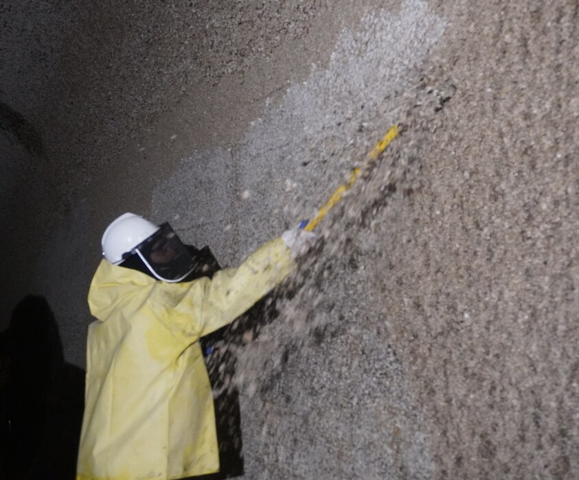 Photo of a person in safety gear scraping barnacle buildup along filling tunnels.