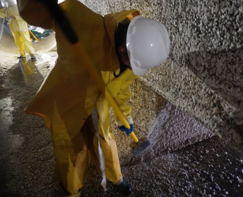 A Corps of Engineers employee scrapes barnacle buildup along filling tunnels.
