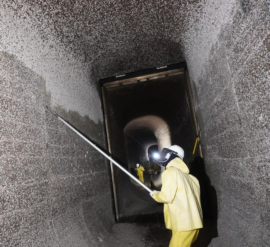 Corps of Engineers employees volunteer to scrape barnacle buildup along filling tunnels.