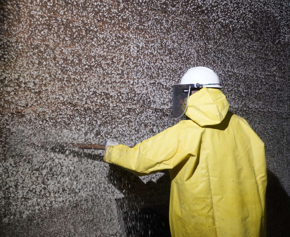 A Corps of Engineers employee scrapes barnacle buildup alongl filling tunnels.