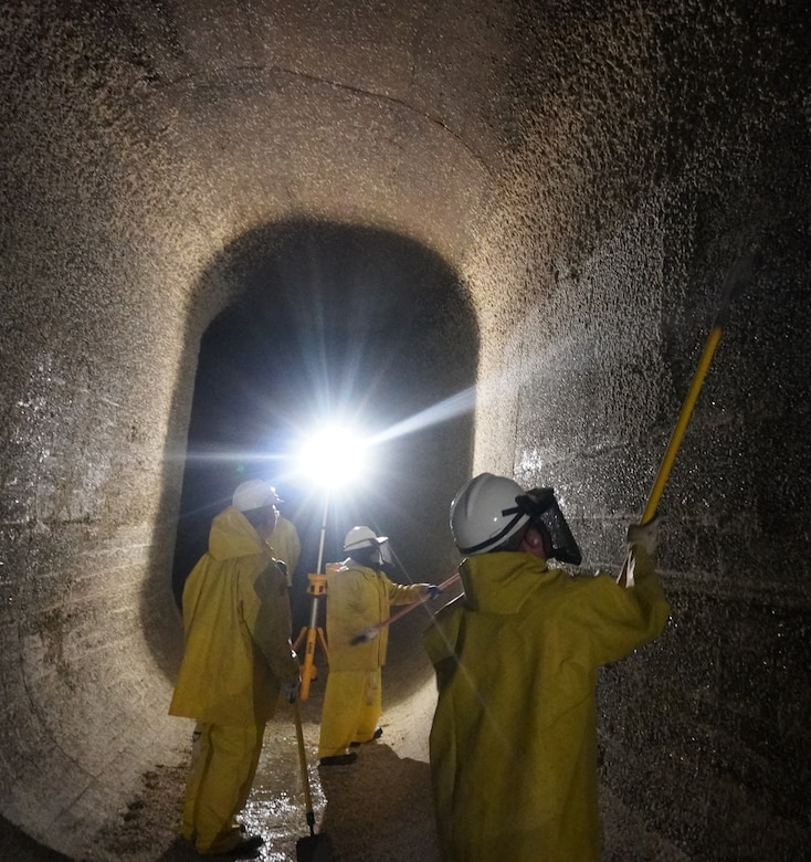 Corps of Engineers employees volunteer to scrape barnacle buildup along the filling tunnels.