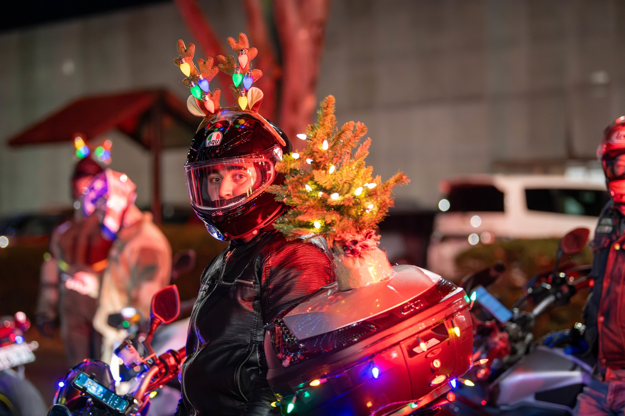 A motorcyclist wearing reindeer antlers watches families wave to Santa Claus following a tree lighting ceremony at the main chapel on Yokota Air Base, Japan.