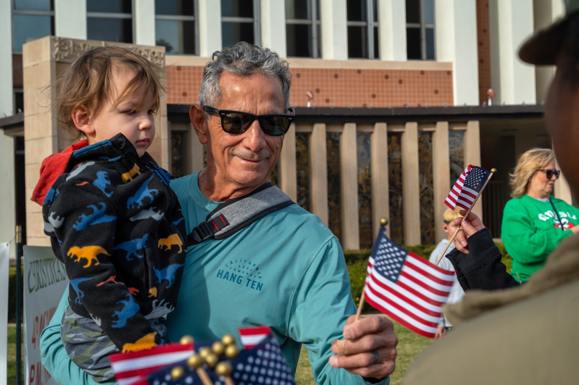 A Phoenix resident receives a flag from a member of the 56th Fighter Wing during the Fiesta Bowl Parade, Dec. 16, 2023, in Phoenix, Arizona.