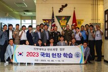 Students and faculty with Korea National Defense University pose for a group photo with U.S. Marine Corps Col. William Pacatte, the commanding officer of Marine Corps Air Station Futenma, during a tour on MCAS Futenma, Okinawa, Japan, Oct. 13, 2023. MCAS Futenma recently hosted students from the Korea National Defense University, highlighting the base's role in international cooperation and regional security. This visit emphasized the significance of the alliance between South Korea and the U.S. in preserving peace in the Indo-Pacific region. (U.S. Marine Corps photo by Cpl. Jonathan A. Beauchamp)